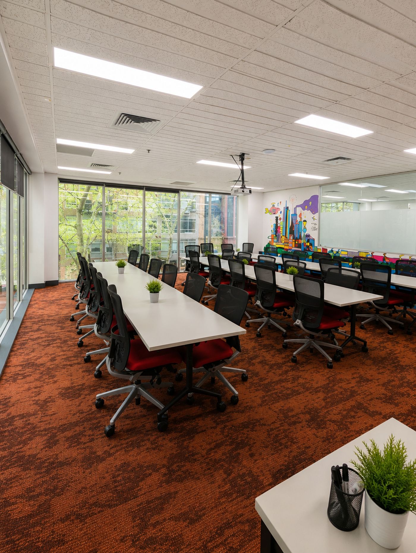 Long training room with rows of desks, red chairs and floor-to-ceiling windows